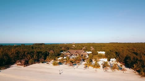 Fantastic-forwards-slowly-sinking-drone-shot-from-the-sea-to-a-luxurx-villa-at-dream-sunset