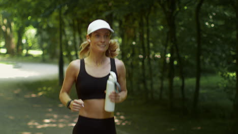 woman jogging in a park with a water bottle