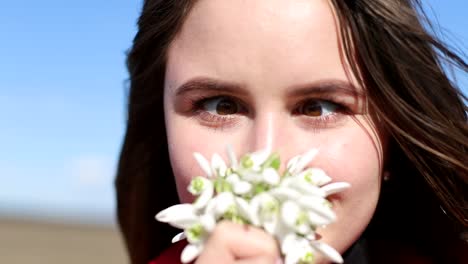 beautiful smiling brunette girl holding bouquet of snowdrops first spring flowers beautiful smiling brunette girl holding bouquet of snowdrops first spring flowers girl holding flowers and smiling to camera spring flowers