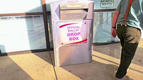 Old-Man-Drops-Mail-in-Ballot-Letter-in-Slot-at-Official-Voting-Box-with-Official-Ballot-Drop-Box-Sign-for-American-Democratic-Election