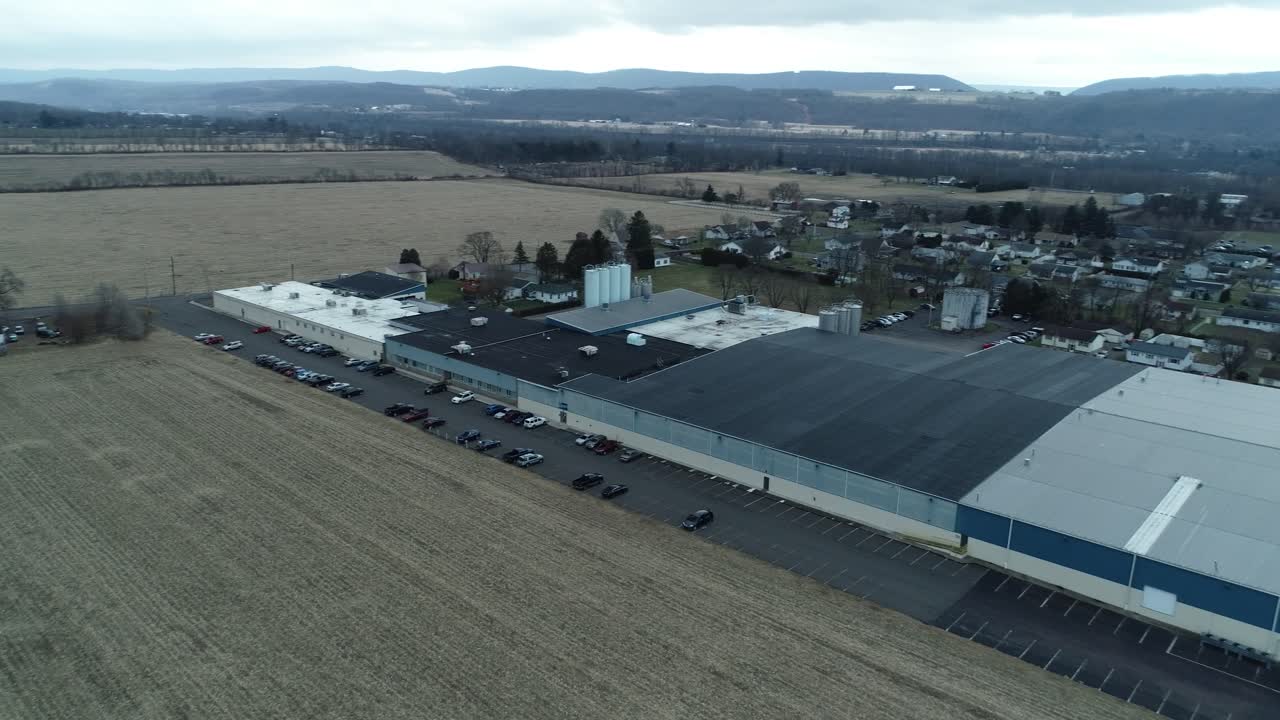A drone shot moving sideways through a city, passing over commercial buildings and nearby homes in a mixed urban neighborhood