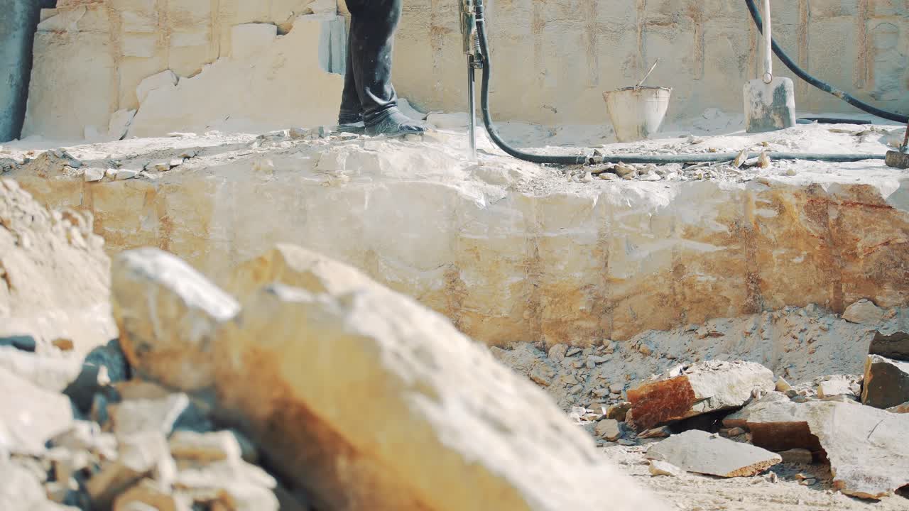 Workers in a stone quarry is drilled block of granite hammers. Pneumatic drill breaking stone