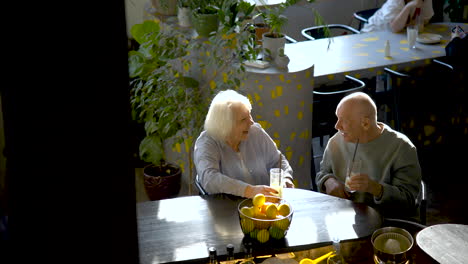 top view of a senior couple drinking limonade and laughing while they are sitting in a bar at sunset