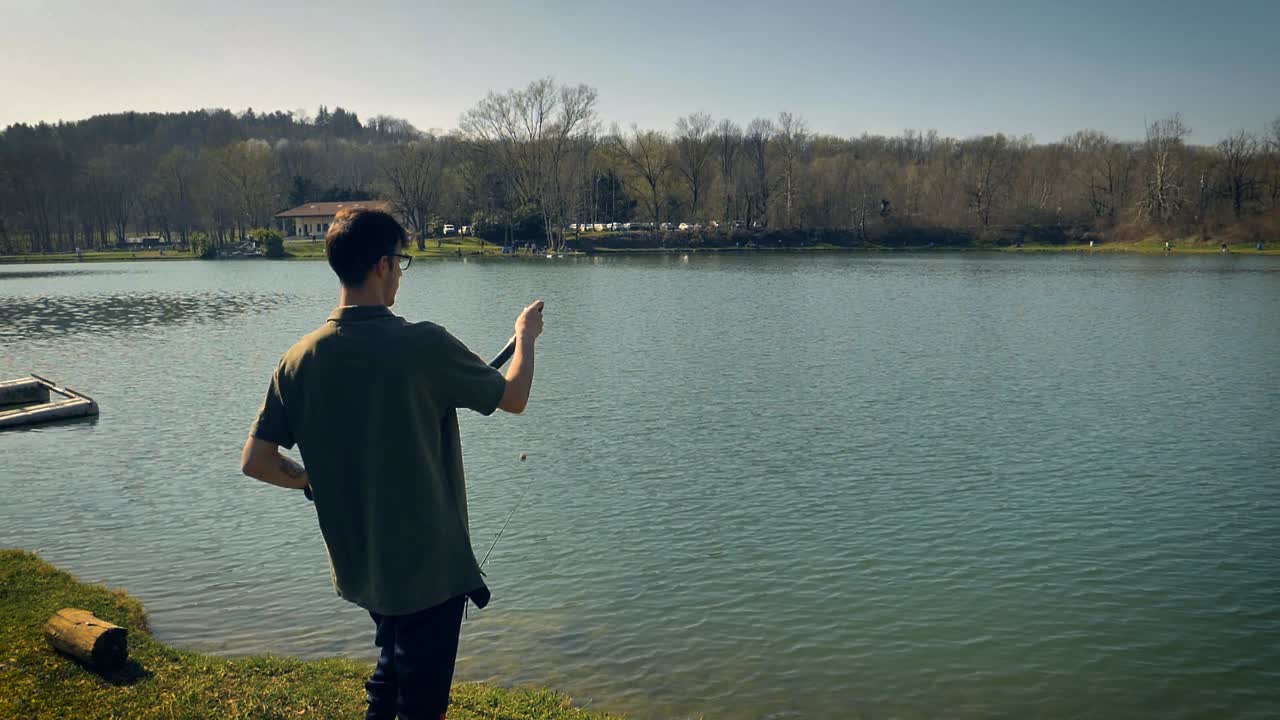 잉어를 낚는 남자가 낚시줄에 물고기를 유인하기 위해 미끼를 물에 던집니다.