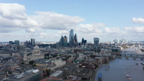 Backwards-fly-above-city.-Aerial-panoramic-view-of-Thames-river-north-bank-with-St-Pauls-Cathedral-and-modern-tall-office-buildings-in-City-district.-London,-UK