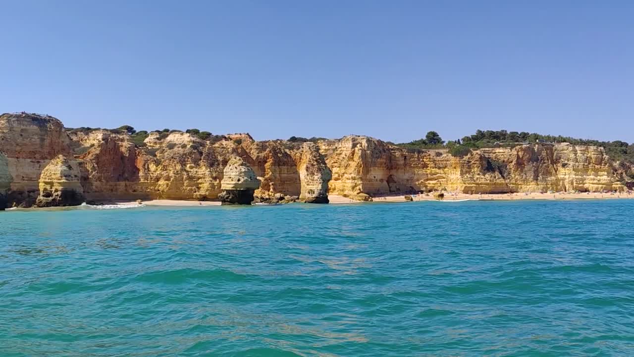 Playas de arena con un fondo rocoso colorido y un océano azul.