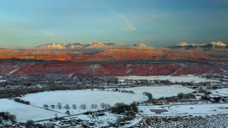 panoramic aerial view of a snowy winter valley with red rock mountains