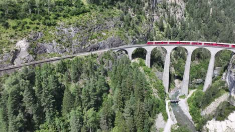 aerial view of the landwasser viaduct as a red train crosses the bridge, showcasing the impressive engineering of the viaduct