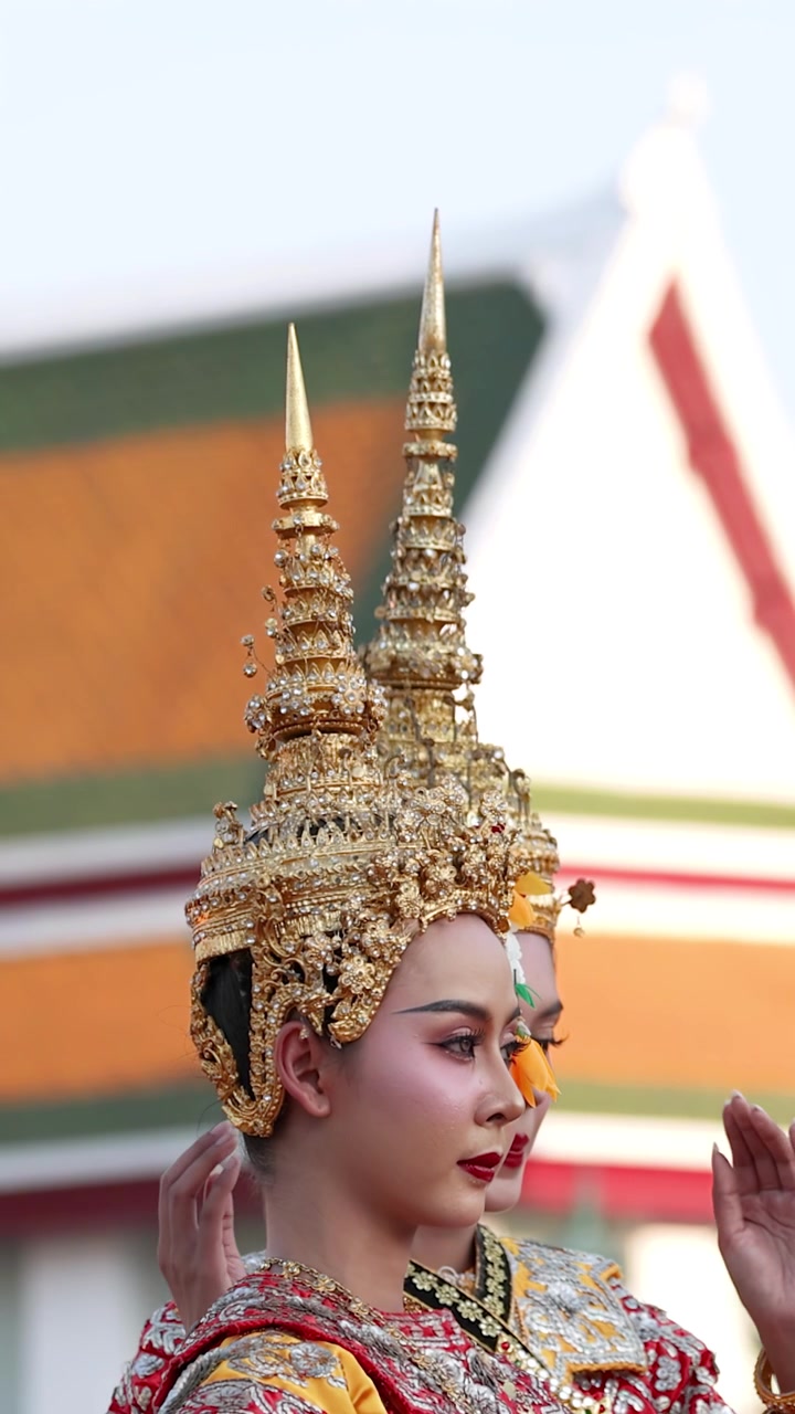 Vista di profilo di una ballerina thailandese che esegue movimenti classici in un elaborato costume dorato all'aperto.