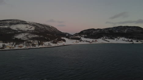 tiro de drone volando sobre el océano hacia una cordillera en noruega