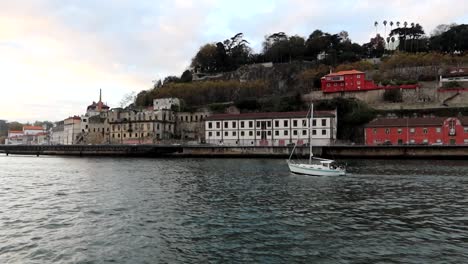 tracking a lone boat sailing the douro river in porto at sunset