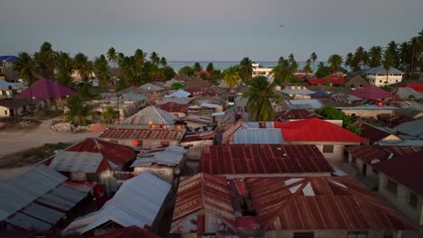 Explore-picturesque-Paje-town,-Zanzibar:-palm-trees,-blue-rooftops,-distant-mosque,-vast-sand-sports-ground