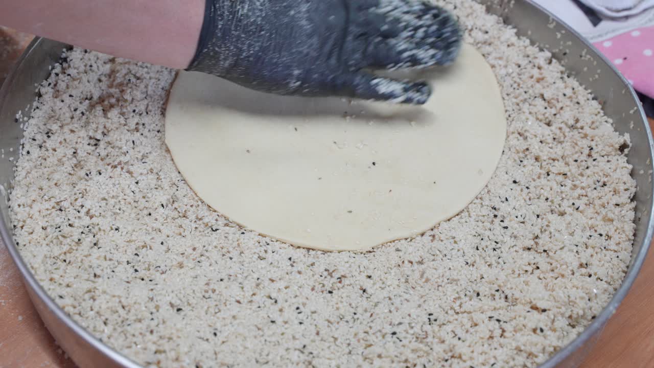 primer plano de la colocación de la masa de pastelería en semillas de sésamo para cubrir la superficie exterior de los pasteles de flaouna recién hechos