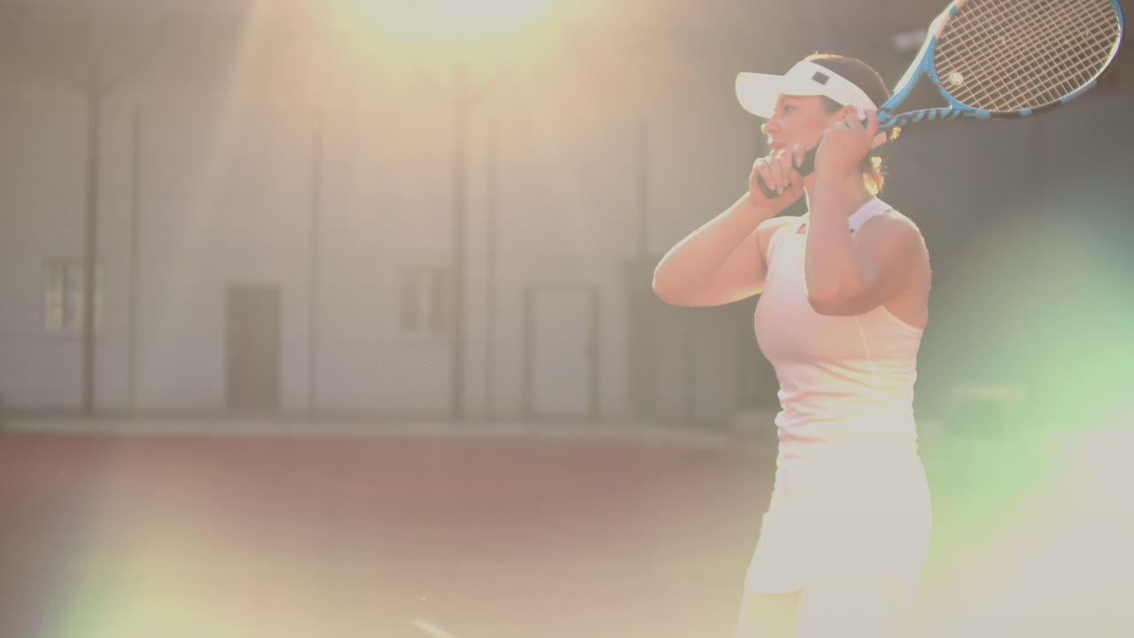 테니스 선수가 공을 때리기 위해 손을 고 있다. 여자 테니스 선수는 코트에서 테니스 공을 때릴 수 있다.