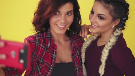 closeup view of two attractive young women posing while taking selfie and showing peace sign