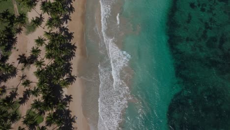 Wide-overhead-aerial-of-ocean-waves-washing-over-Caribbean-beach