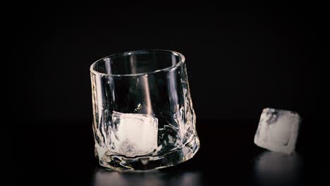 glass and ice cube movement on dark surface