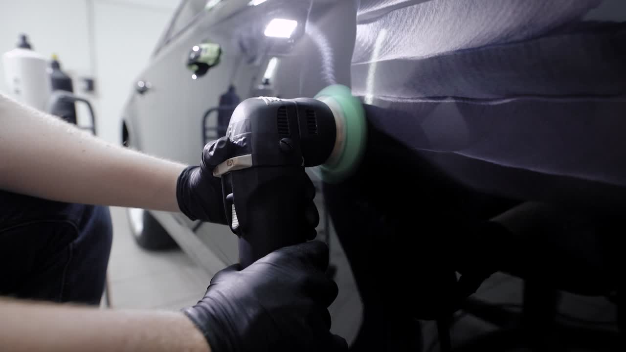 es maestro del procesamiento de la superficie de la carrocería del automóvil mediante una máquina de pulido, aplicando una composición protectora en un garaje