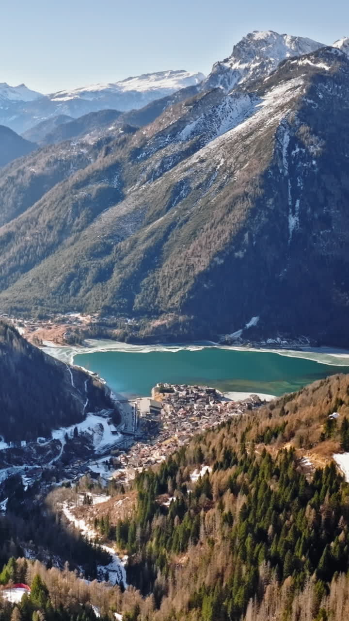 Aerial drone view of the Alleghe village with Lake Alleghe, in the province of Belluno, Dolomites, Italy. Vertical