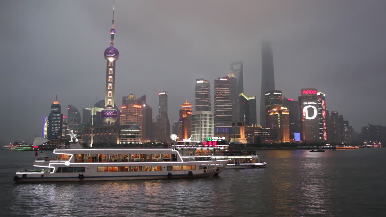 El vívido horizonte nocturno de Shanghái, China, con tráfico fluvial en primer plano.