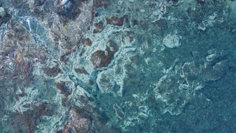 formación rocosa única bajo el mar con olas que se estrellan | foto aérea constante sobre aguas claras de color turquesa | 4k