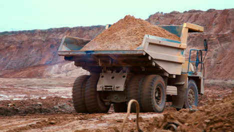 Dirty-tipper-truck-transports-sand-on-road-in-quarry.-Large-yellow-dumper-truck