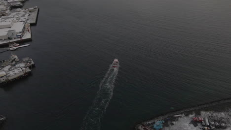 fishing boat leaving harbour towards the fishing grounds of the arctic, aerial