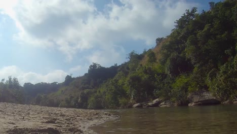 bosque verde con río que fluye y cielo azul brillante por la mañana desde un ángulo plano