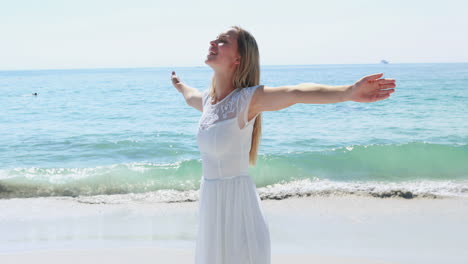 mujer rubia feliz con los brazos extendidos en la playa