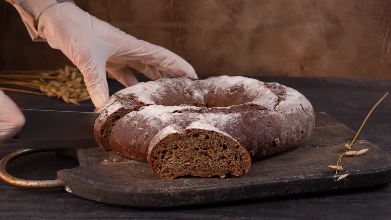 The chef cuts homemade sourdough bread loaf into slices with kitchen knife