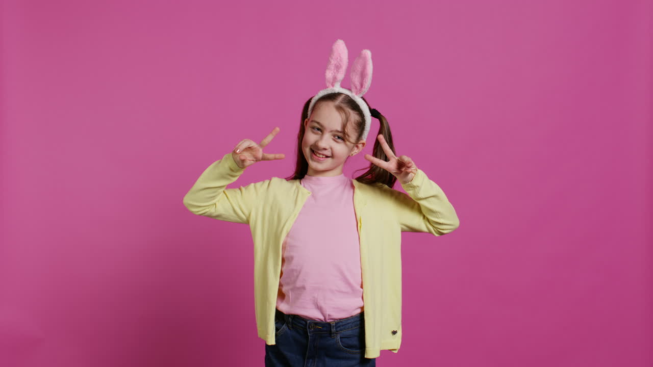 스튜디오에서 평화의 표지판을 보여주는 피그테일을 가진 젊은 즐거운 아이