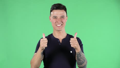 portrait of a handsome young guy is looking at camera and pointing side hand for something then shows thumb like. green screen