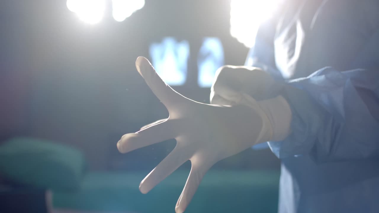 sección media de una cirujana caucásica con guantes médicos en el quirófano, cámara lenta