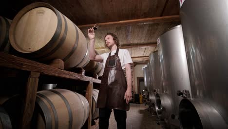 authentic shot of successful male sommelier is tasting a flavor and checking white wine quality poured in transparent glass in a wine cellar.