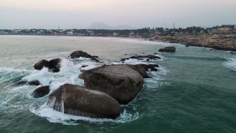 aerial drone shot of kanyakumari with the sprawling city and endless ocean glowing in the evening light.