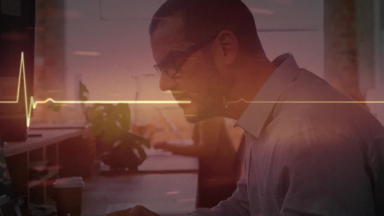 monitor de ritmo cardíaco rojo brillante contra hombre caucásico usando computadora en la oficina