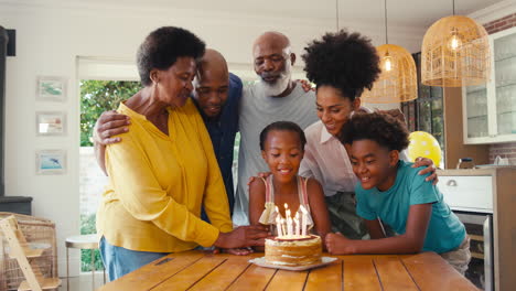 multi-generation family celebrating granddaughter's birthday with cake and candles at home