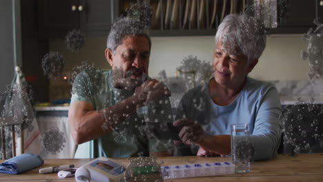 animation of covid 19 cells over senior couple using smartphone at home