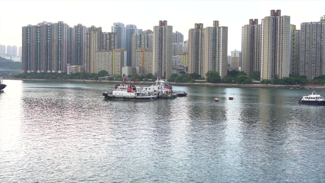 dos barcazas en el agua junto a apartamentos de gran altura en hong kong