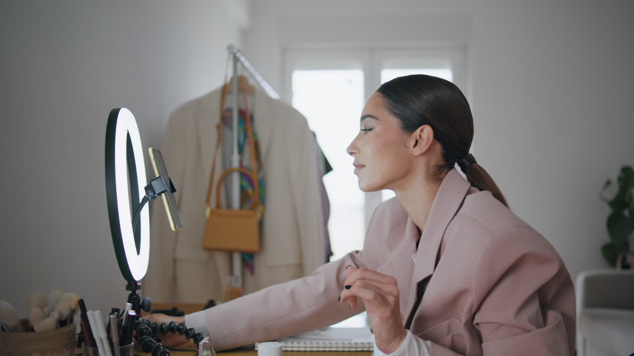 블로거의 아름다움이 빛을 바꾸고 집에서 버튼을 누르고 있습니다. 전화를 사용하는 여성