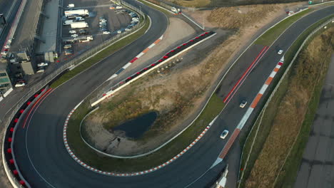 f1 racing cars moving on a sharp turn on the circuit of zandvoort, the netherlands - aerial drone shot