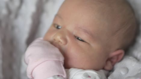 beautiful caucasian newborn baby girl with pink mittens - close up shot