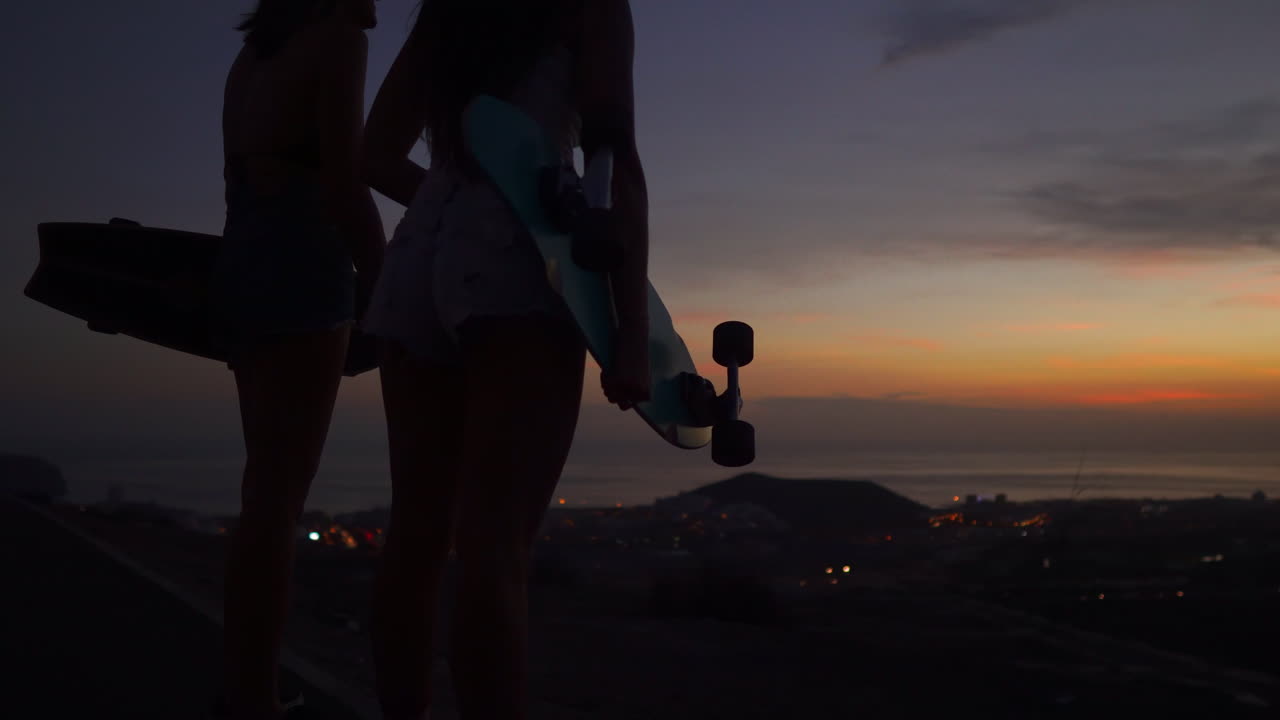 Enjoying the mountain's summit after skateboarding, friends gaze at the beautiful sunset