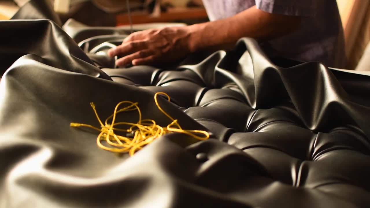 person with the profession of upholsterer placing buttons on a headboard-tilt down