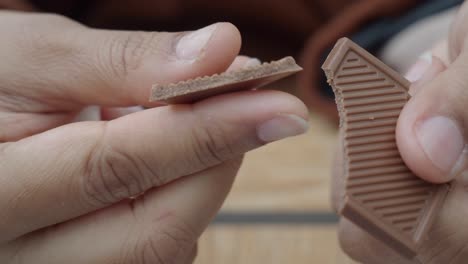 cerca de la mano de una persona rompiendo una barra de chocolate