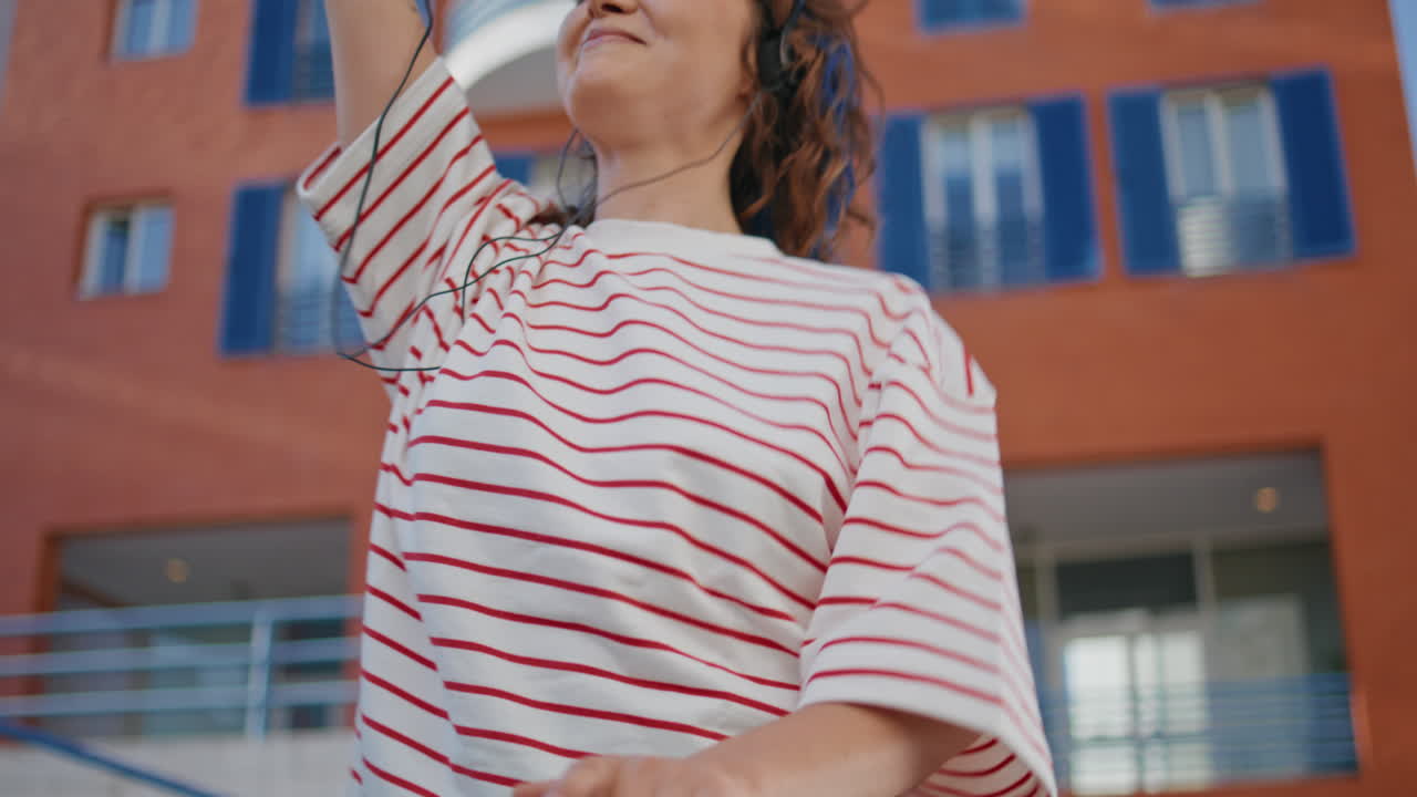 un lindo adolescente bailando con auriculares sosteniendo barandillas urbanas en la calle de cerca.