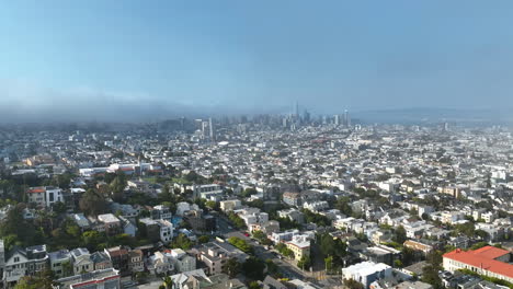 aerial view backwards through fog and over the san francisco cityscape. sunny day