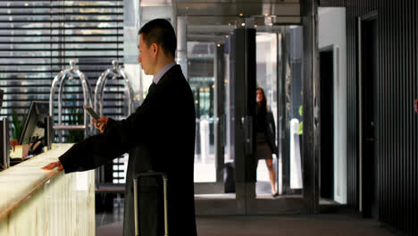 Side-view-of-asian-businessman-using-mobile-phone-at-reception-in-a-modern-hotel-4k