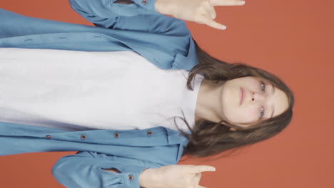 Vertical-video-of-Young-woman-doing-rocker-sign-and-dancing.