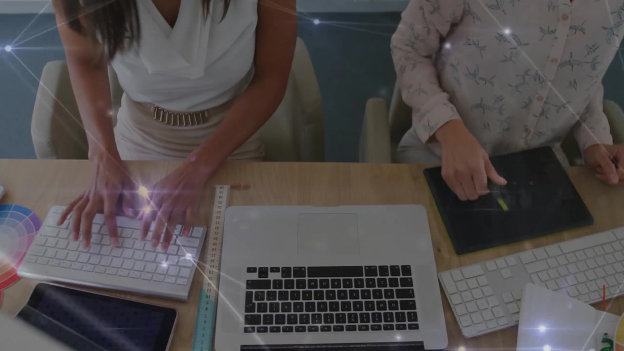 Designer che collaborano, uno che indica un tablet e digita sulla tastiera mentre un collega schizza.